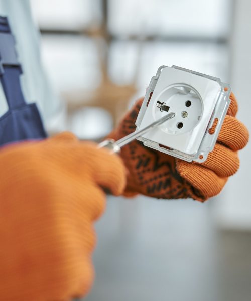 Male electrician hands fixing electrical wall socket